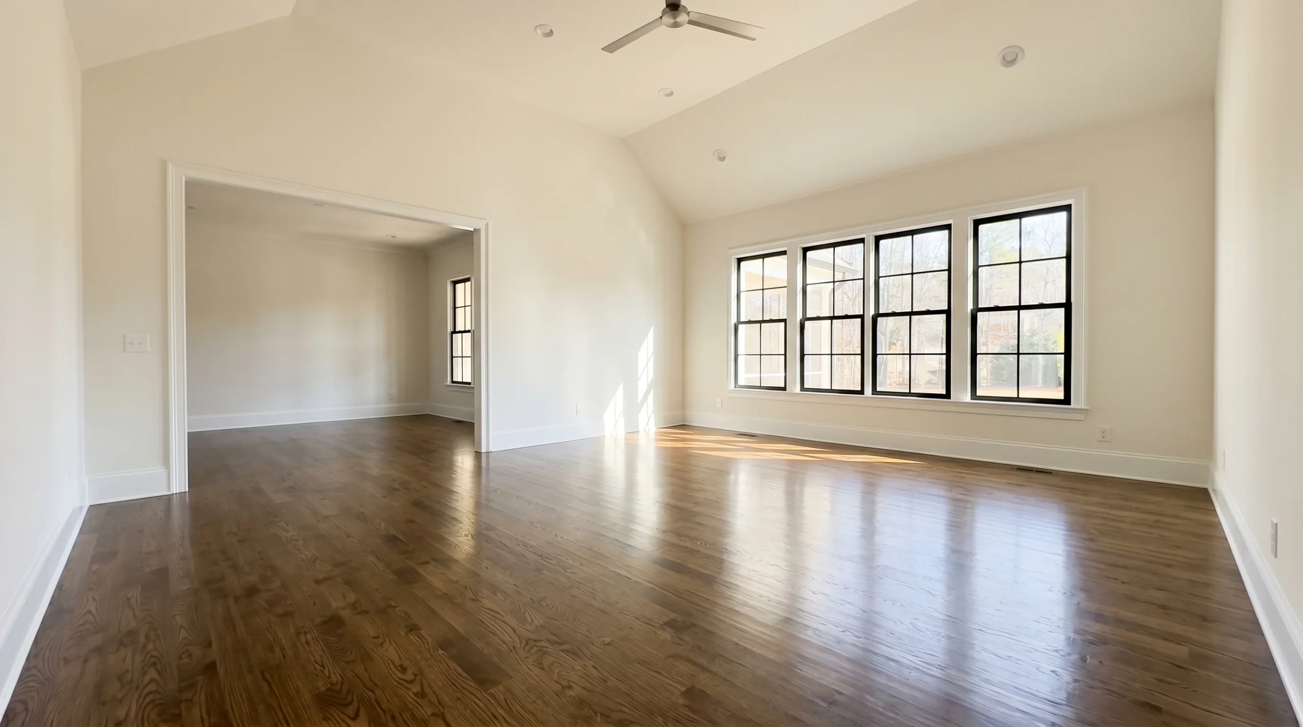 Empty room with vaulted ceiling and gleaming hardwood floors after post-construction cleaning service